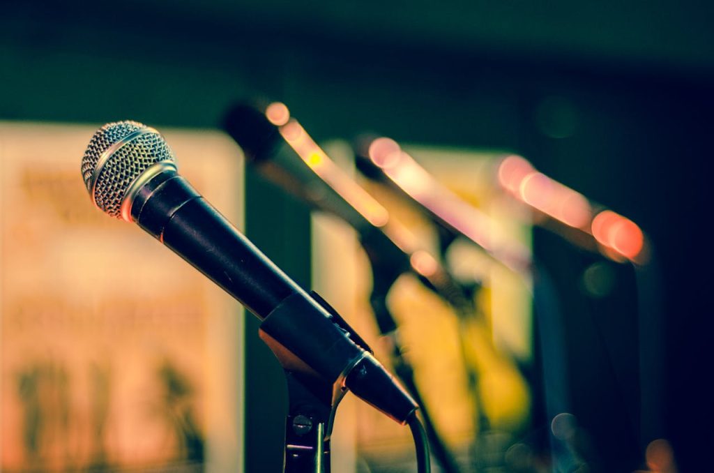 pexels photo Microphones in focus with colorful blurred background, ideal for music events.