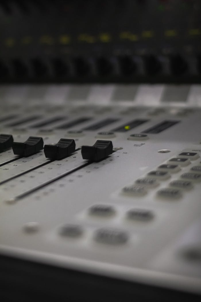 Detail shot of an audio mixing console focusing on the faders and controls.