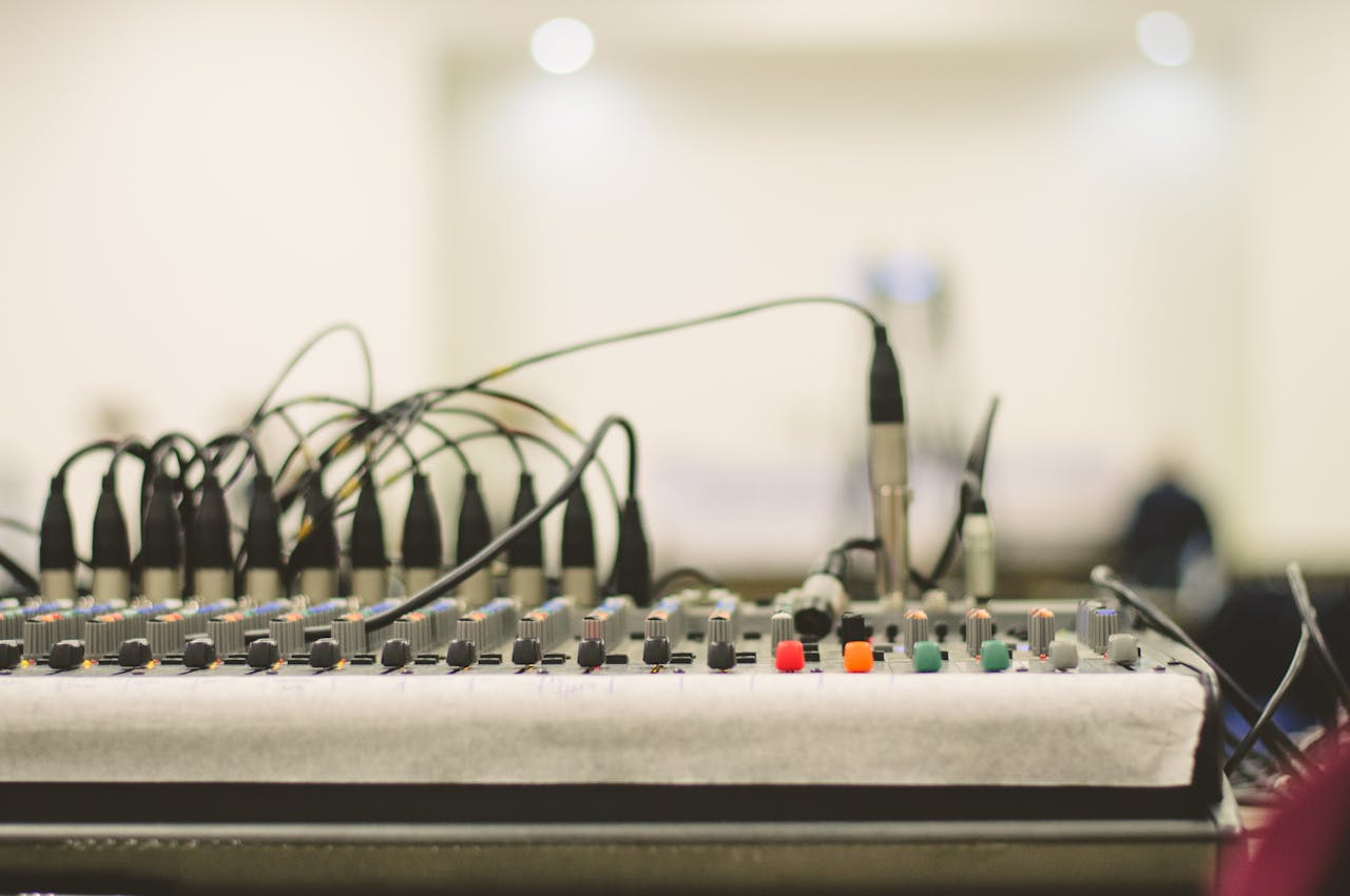 Nos Métiers Detailed view of a professional audio mixing console with knobs, faders, and cables.