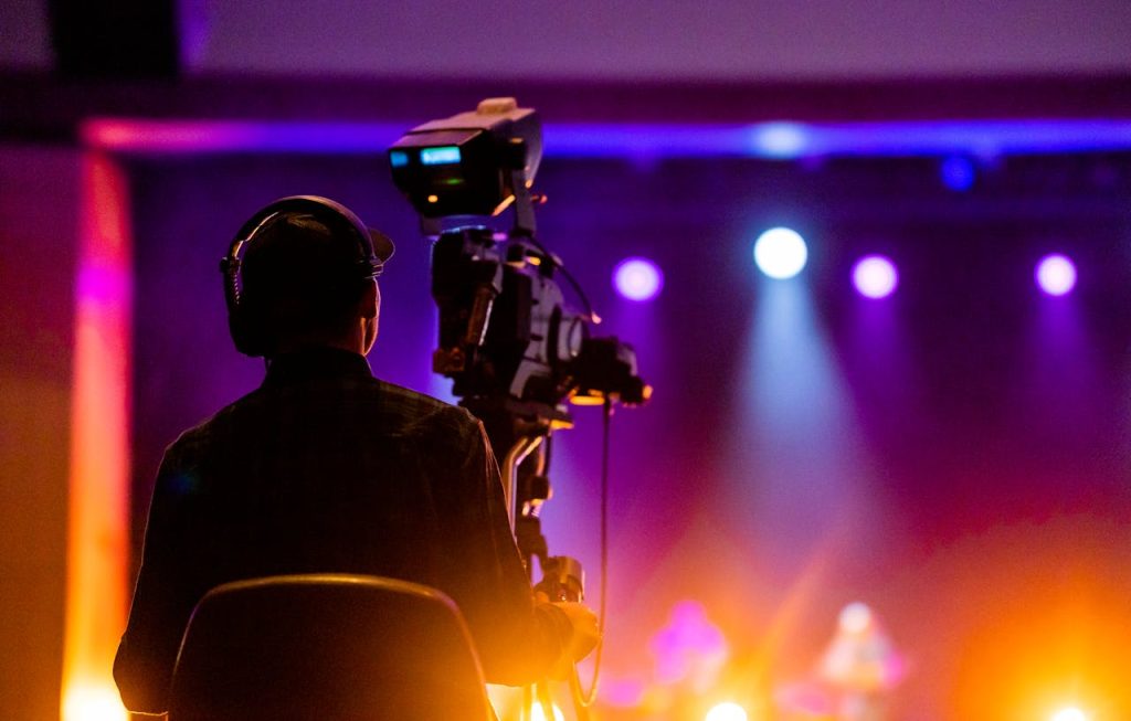 pexels photo 9618875 A videographer recording a live concert with vibrant spotlights, using professional equipment.
